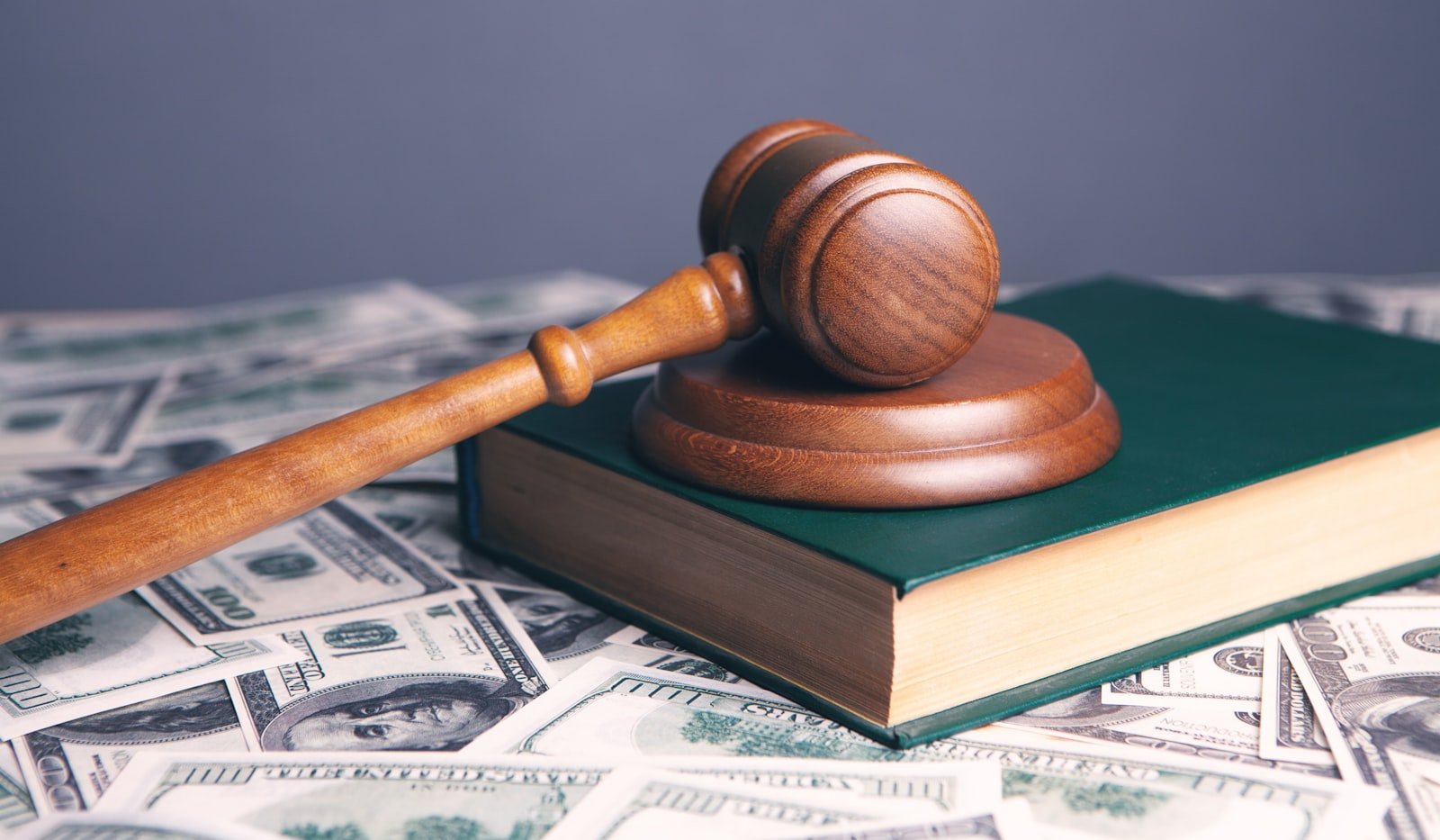 A wooden gavel resting on a closed green law book, symbolizing the legal question students ask before paying for online class help